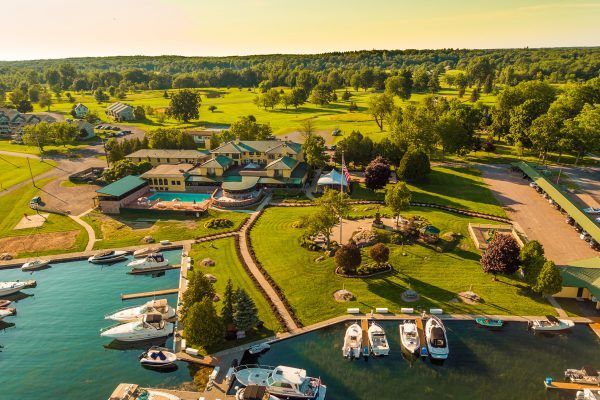 An aerial view of a marina with boats docked and a golf course in the background.