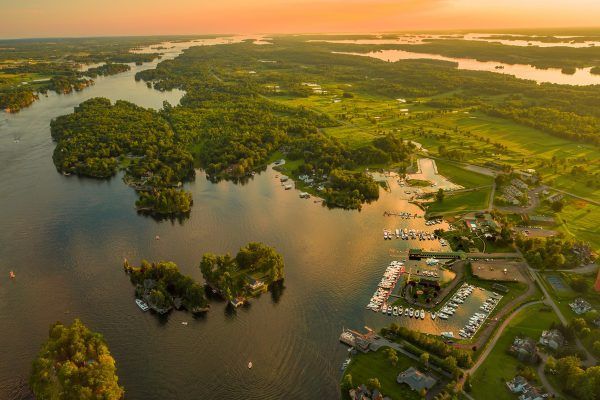 An aerial view of a lake surrounded by trees and houses at sunset.