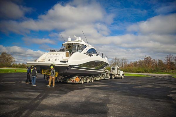 A large boat is being towed by a semi truck.