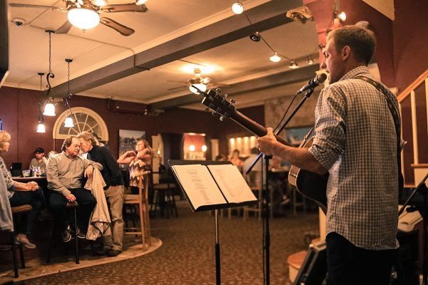 A man is playing a guitar and singing into a microphone in a restaurant