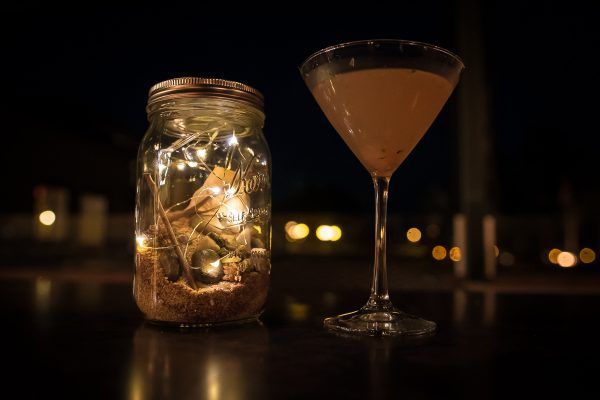 A martini glass next to a jar of lights on a table.