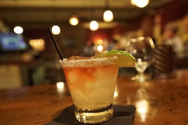 A close up of a margarita with a straw on a bar.