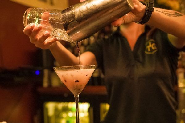 A bartender is pouring a drink into a martini glass.