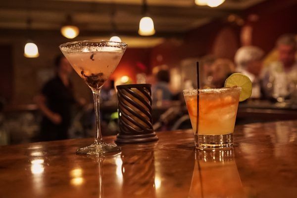 Two drinks are sitting on a bar in a restaurant.