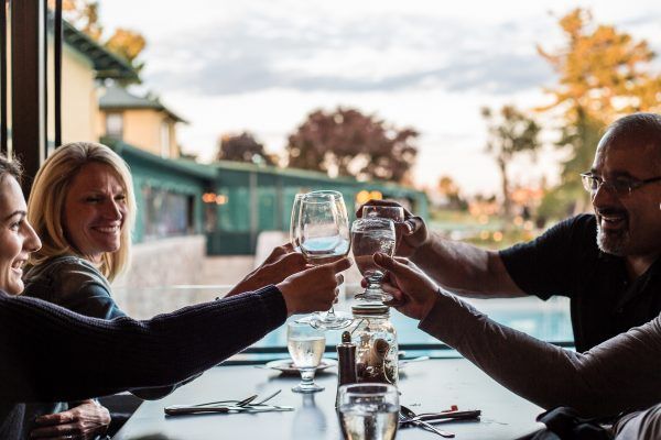 A group of people are sitting at a table toasting with wine glasses.