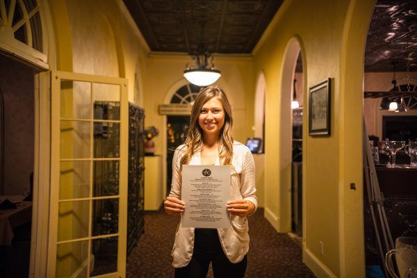 A woman is holding up the Thousand Islands Club Menu.