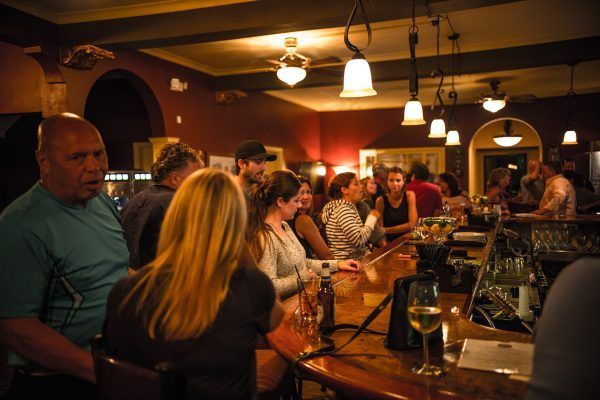 A group of people are sitting at a bar in a restaurant.
