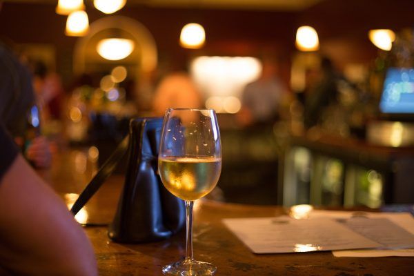 A glass of wine is sitting on a table in a bar.