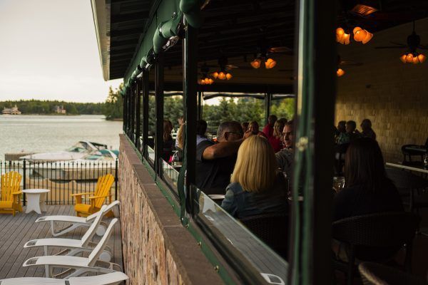 A group of people are sitting on a balcony overlooking a lake.