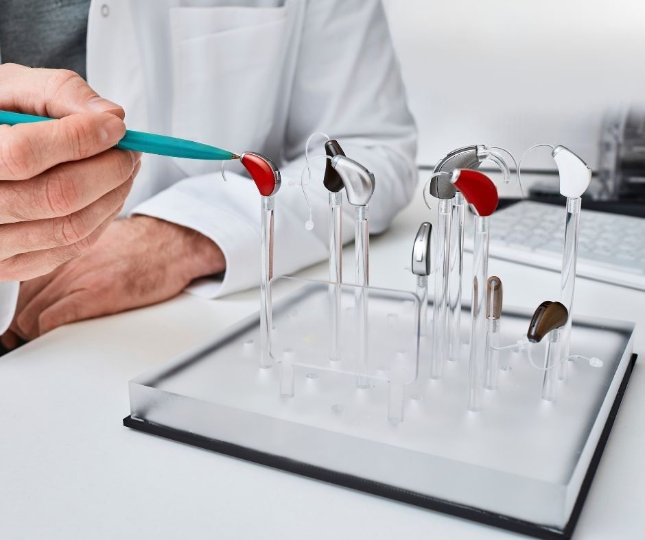 Grembiule di lino beige annodato in vita, con tasca con logo; cucchiaio di legno e ciotola in primo piano.