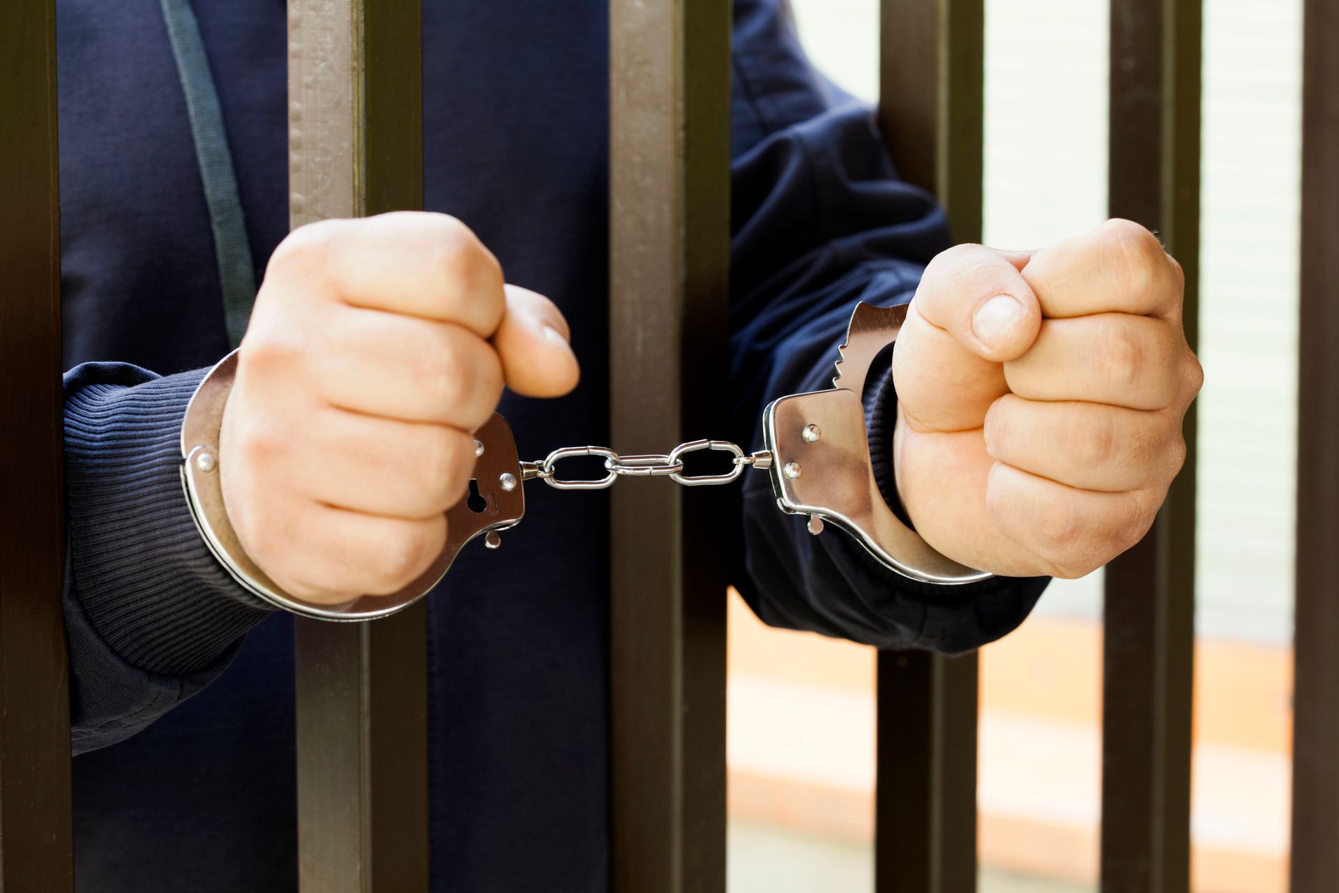 A man in handcuffs is behind a fence.