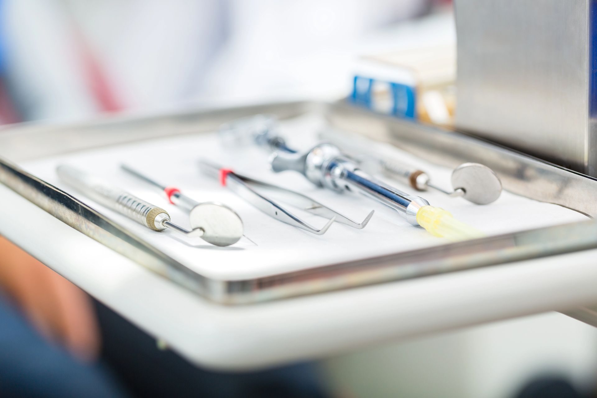 Una persona sorride seduta sulla poltrona del dentista, mentre un professionista con i guanti blu tiene uno specchietto dentale.