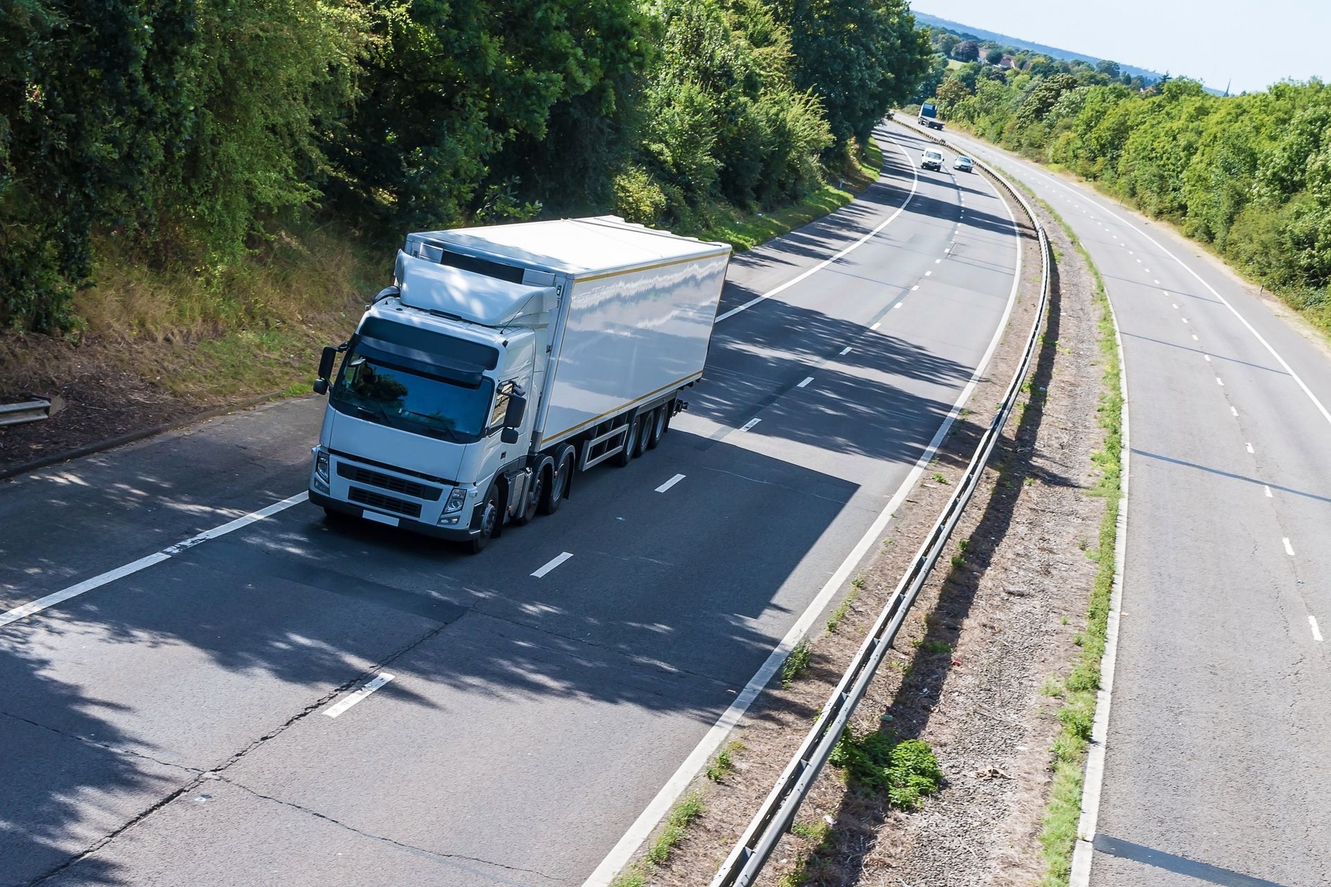 Large lorry carrying cargo on a sunlit highway.