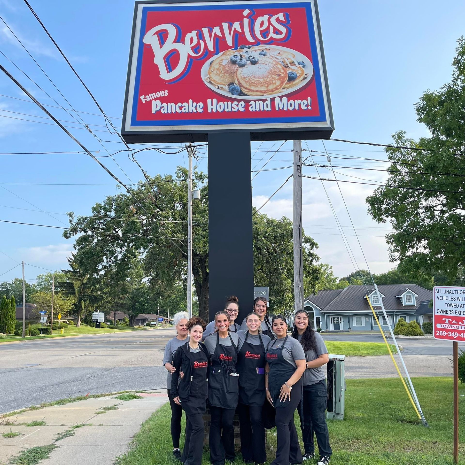 A group of people posing in front of a berries pancake house sign