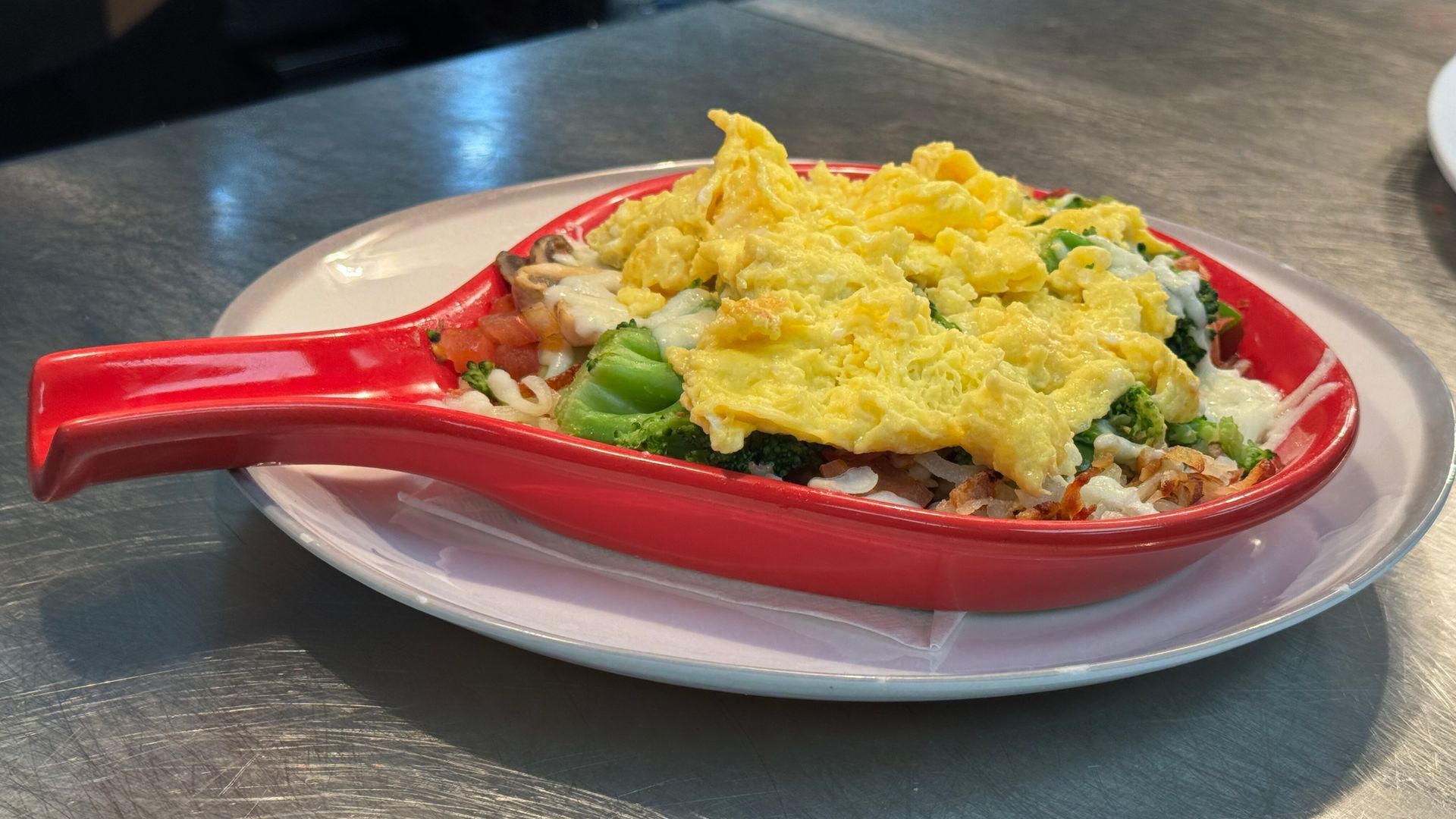 A red spoon filled with food is on a plate on a table.
