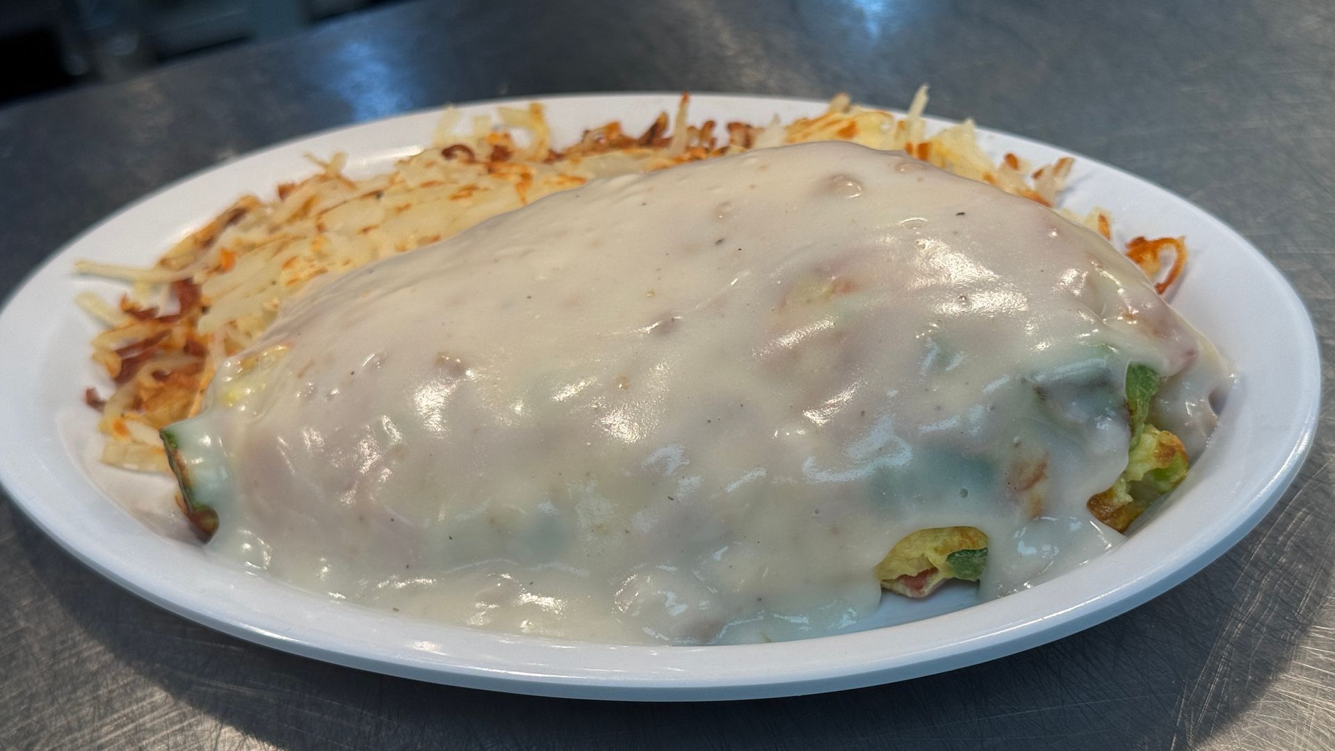 A plate of food with hash browns and cheese on a table.