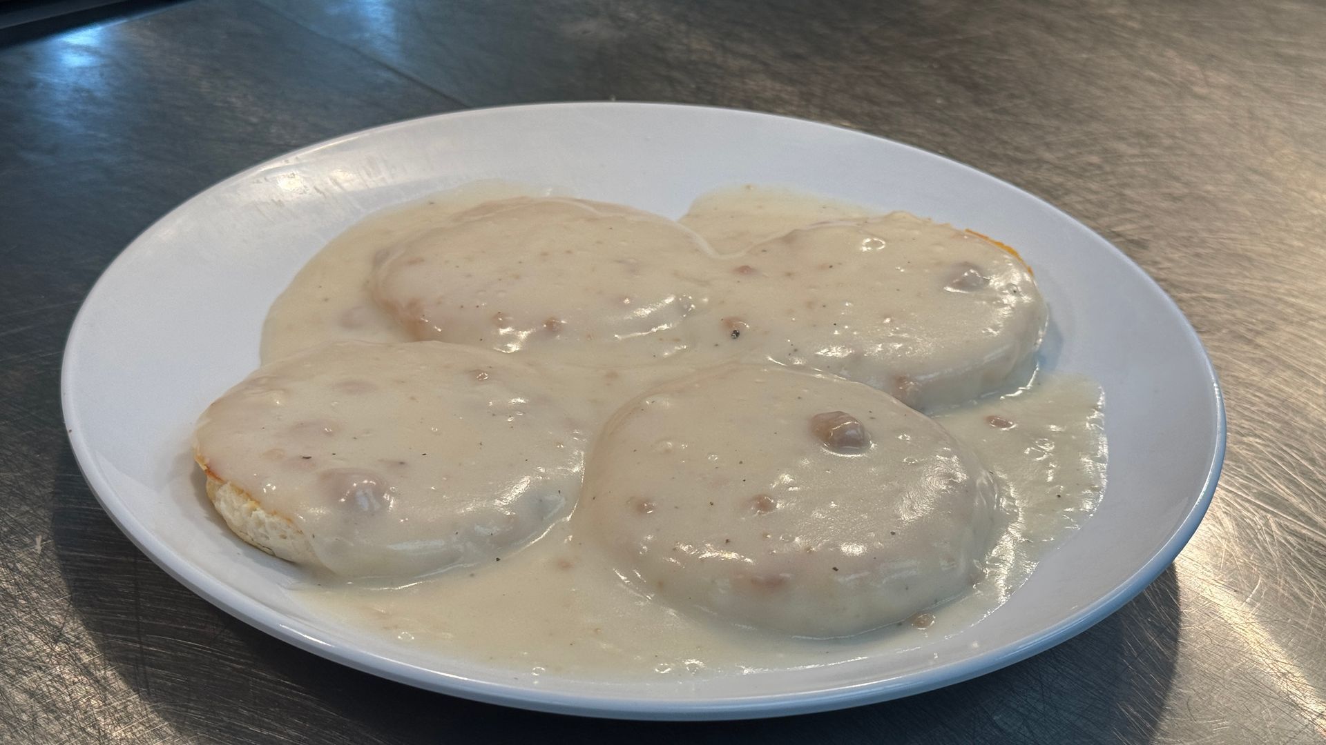 A white plate topped with biscuits and gravy on a table.