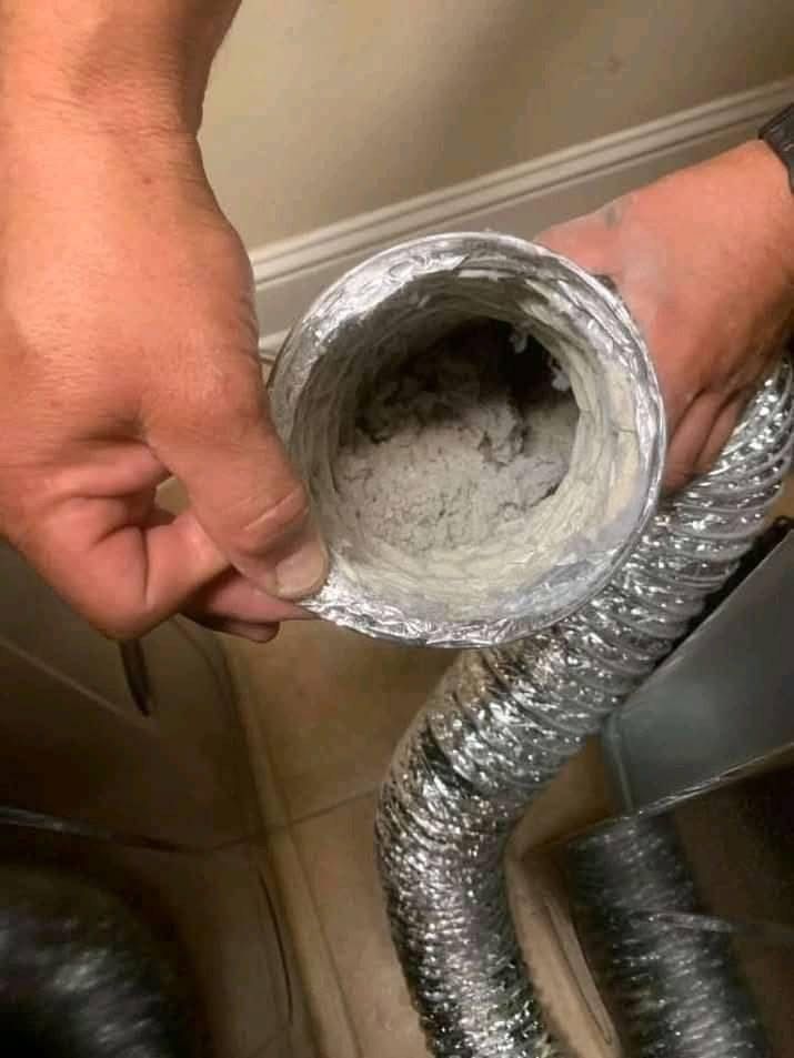 A person is holding a duct with a lot of dust in it.