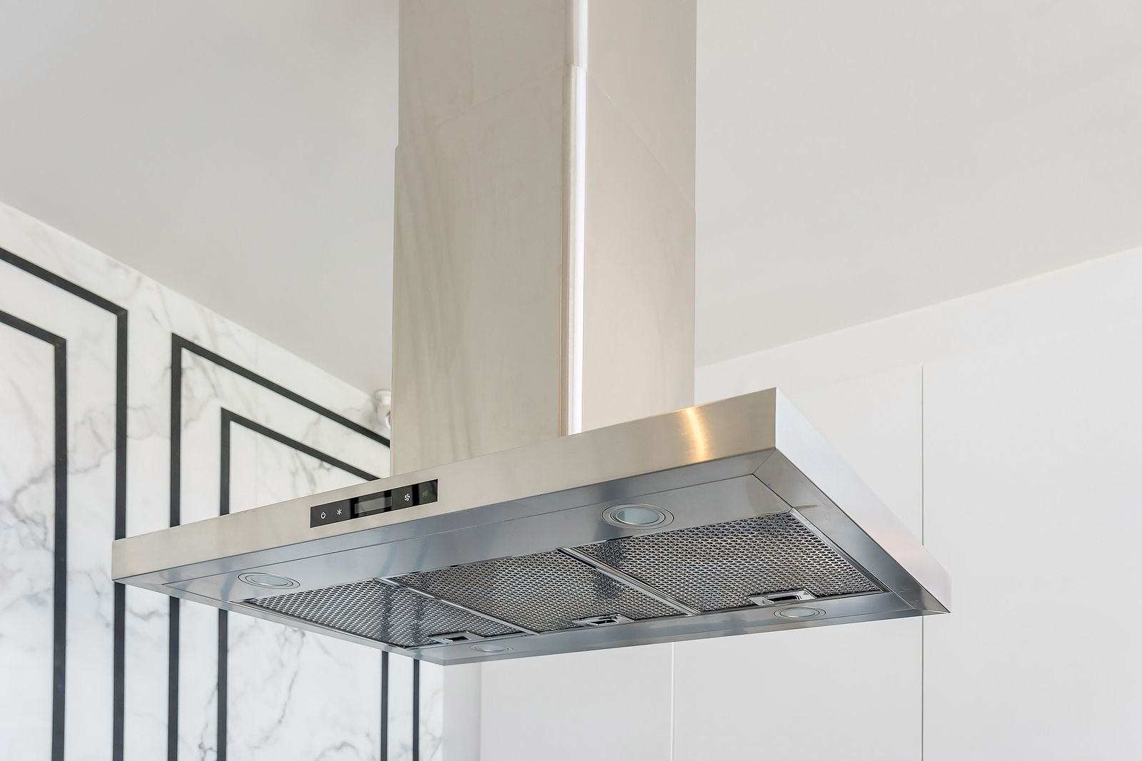 A stainless steel hood is hanging from the ceiling in a kitchen.