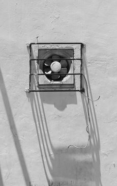 A black and white photo of a fan on a wall