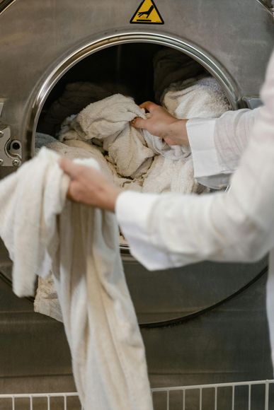 A person is putting clothes in a washing machine.