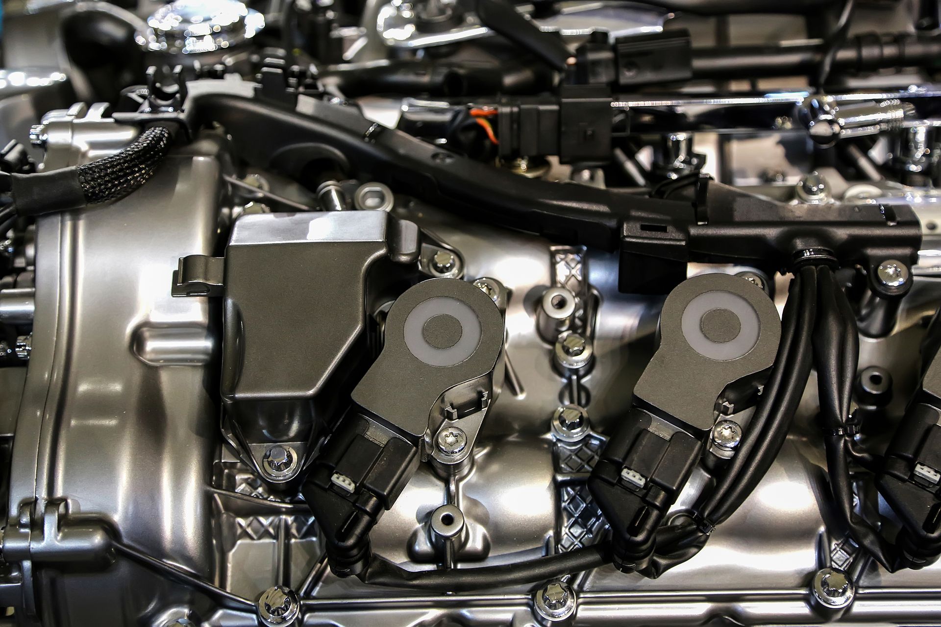 Close-up of a shiny, metallic car engine with black wiring and ignition coils.