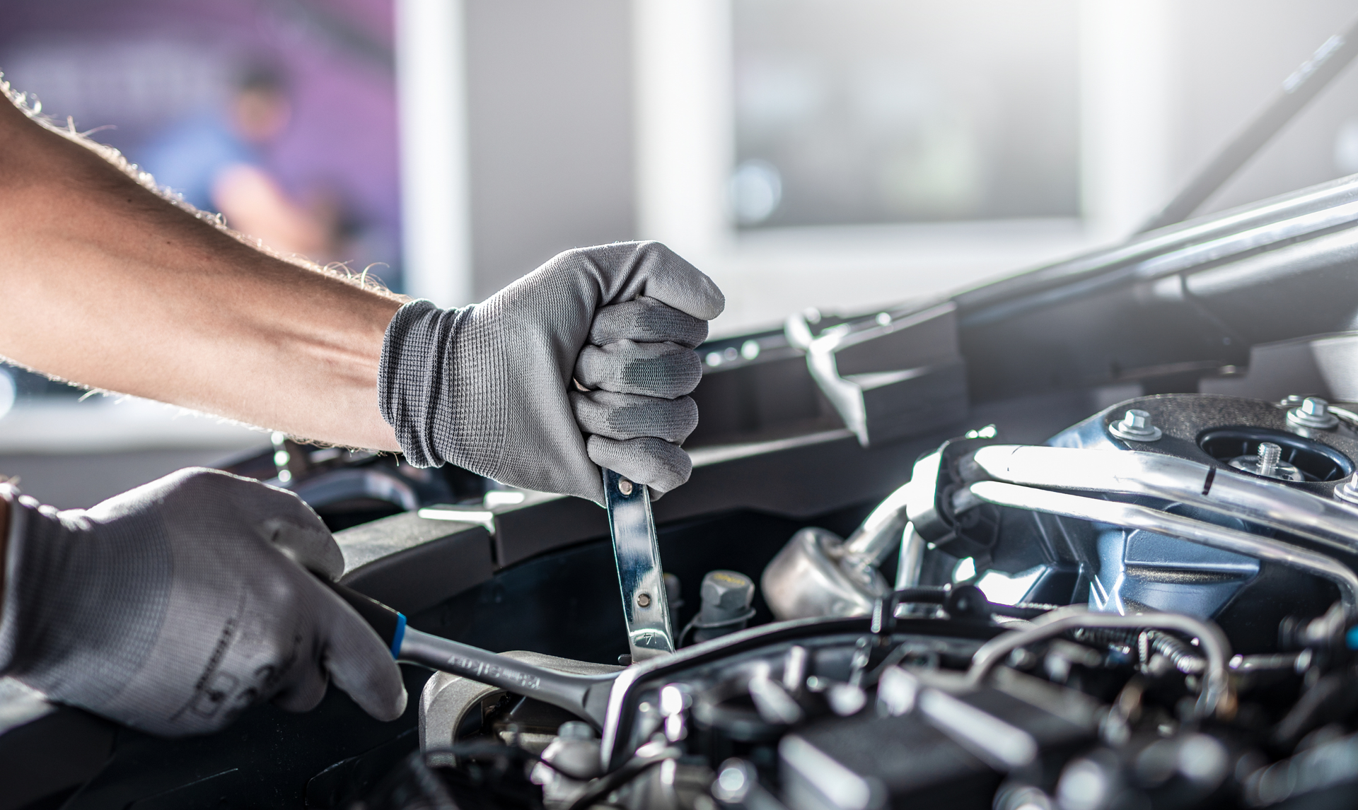 Man hugging a black car, smiling with eyes closed in a car dealership.