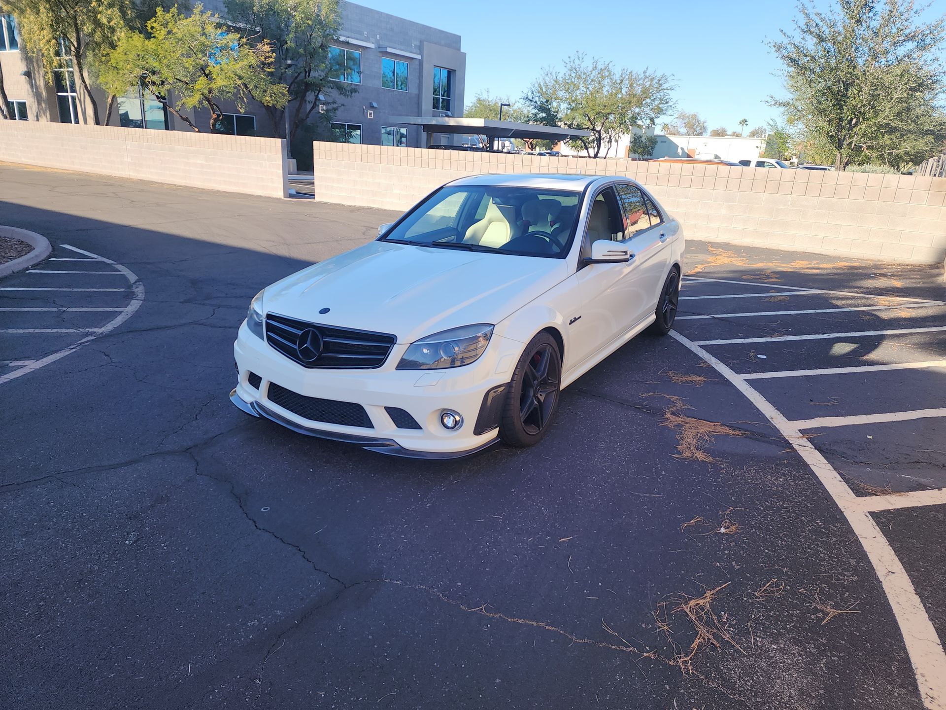 White Mercedes-Benz sedan parked in a lot on a sunny day.