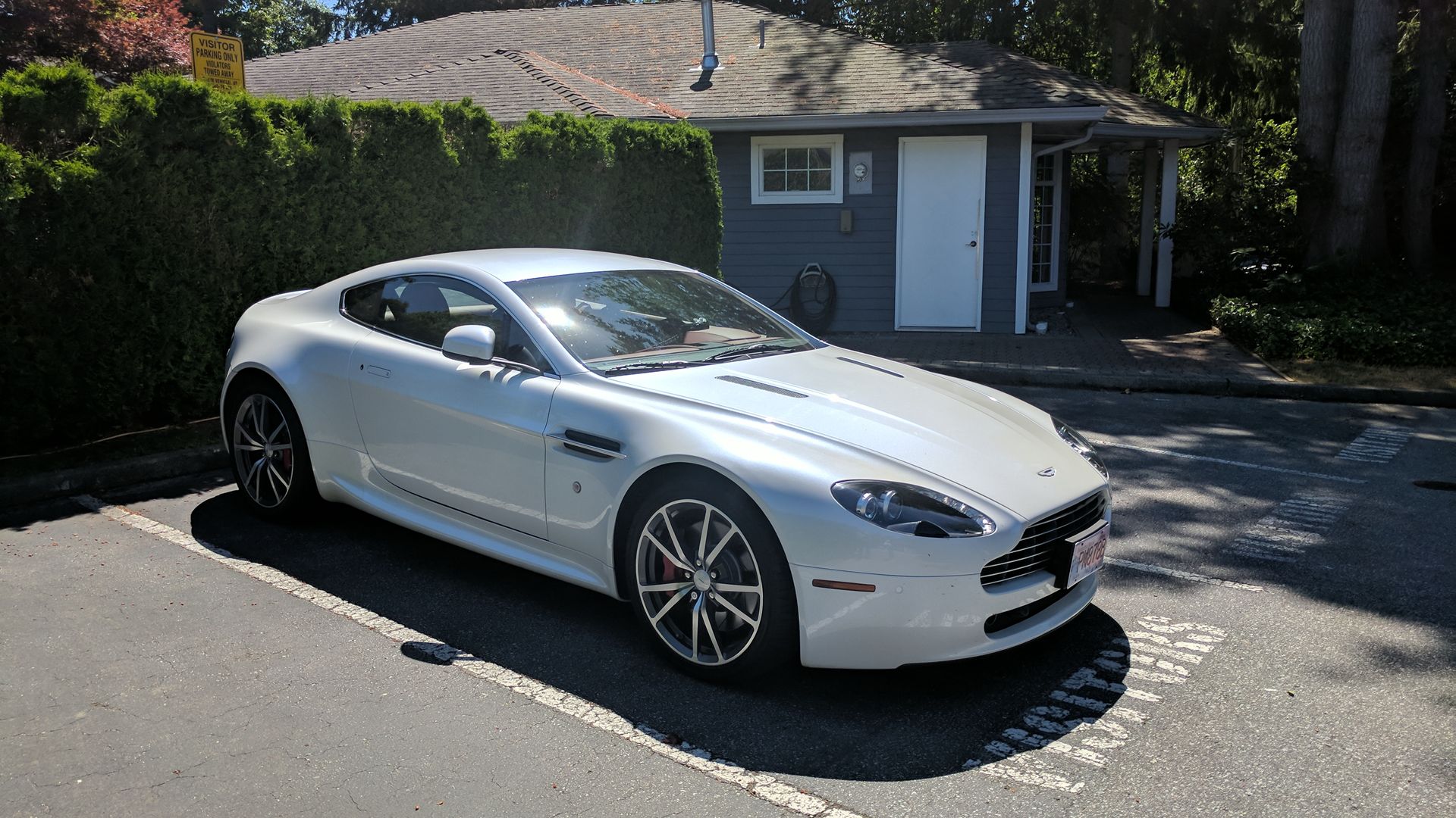 Mechanic in red overalls inspecting undercarriage of a car raised on a lift in a garage.