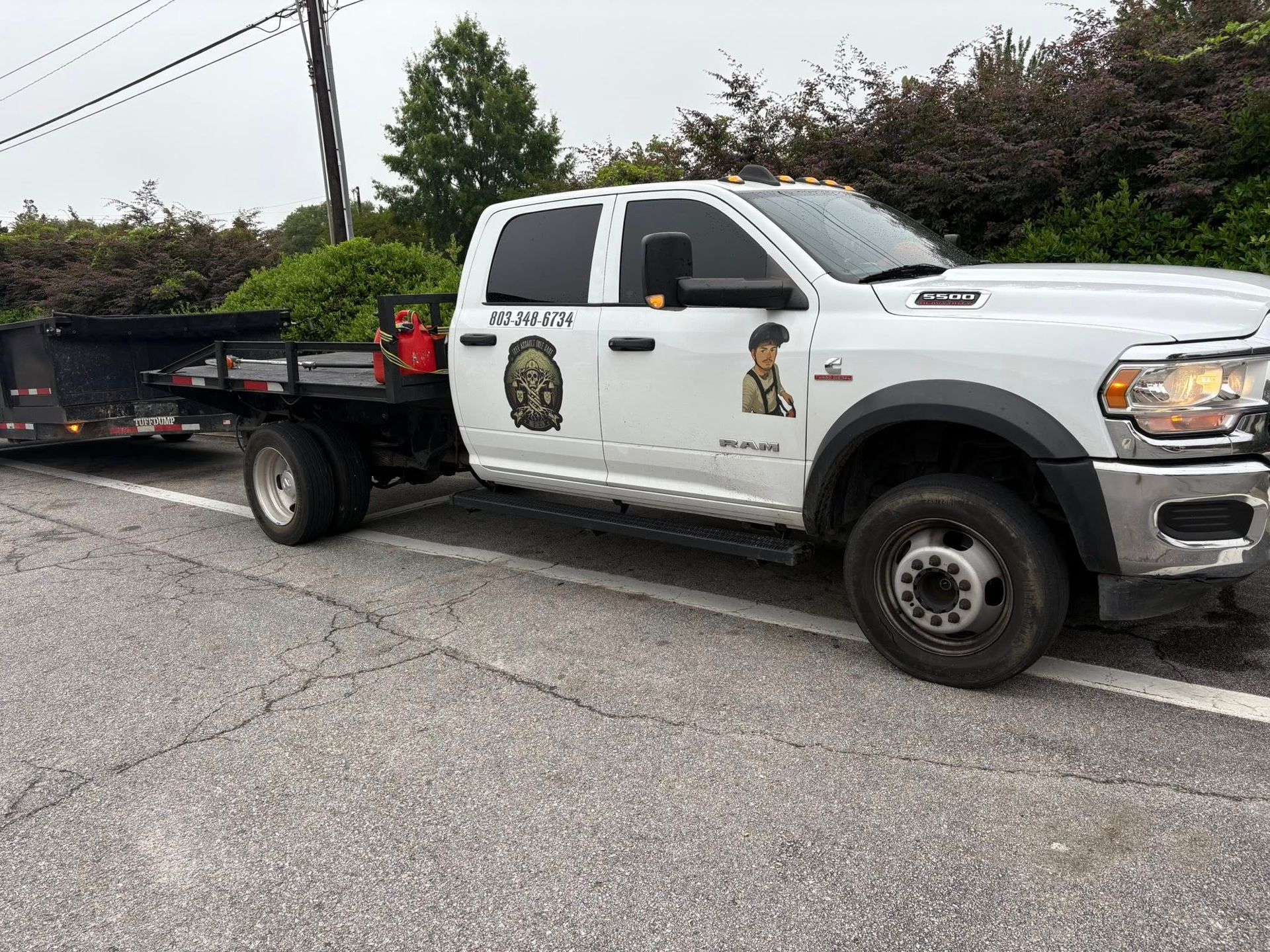 A white truck with a trailer attached to it is parked on the side of the road.