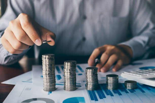 A man is stacking coins on top of each other on a table.