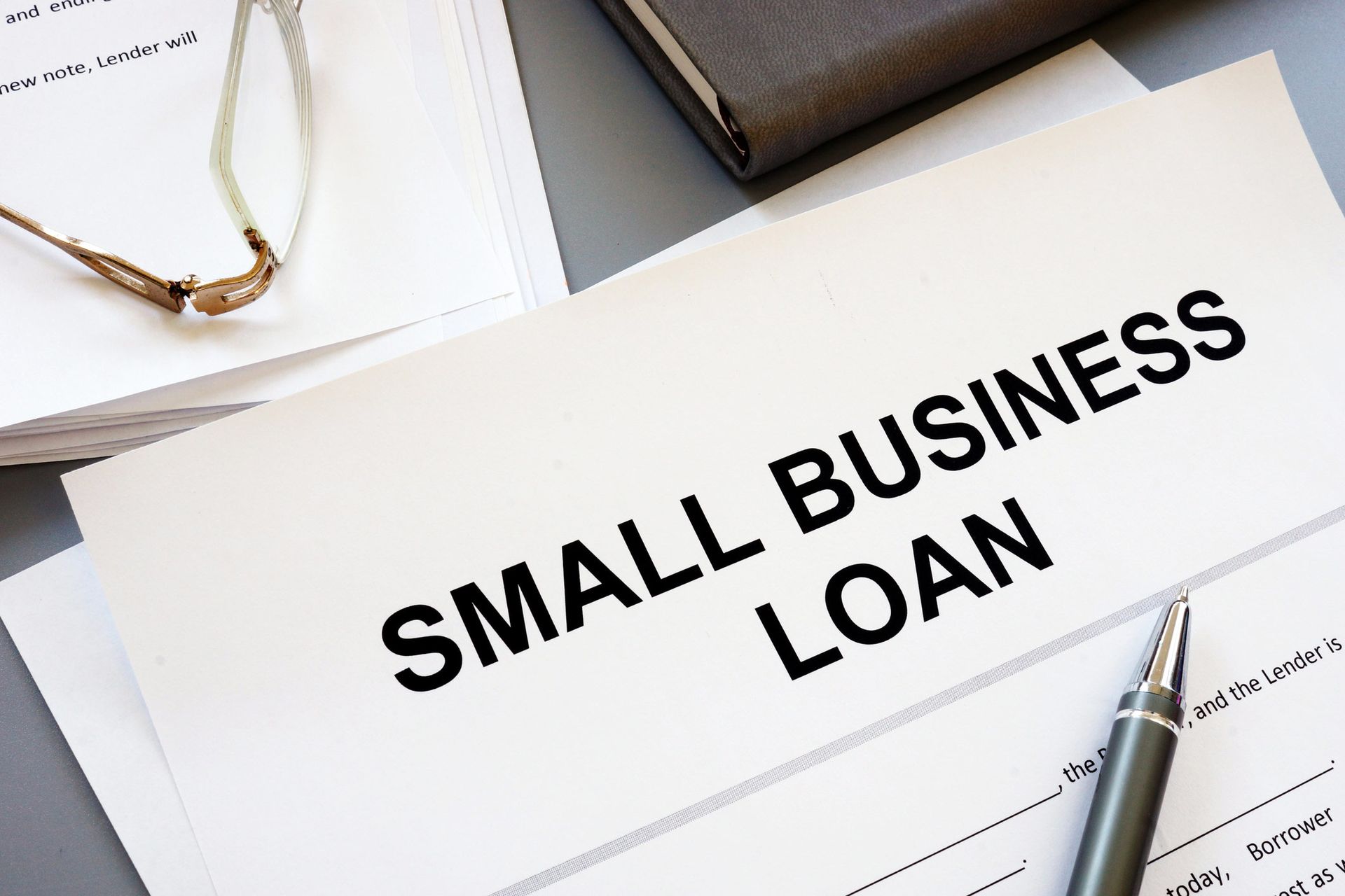 A small business loan form with a pen and glasses on a table.