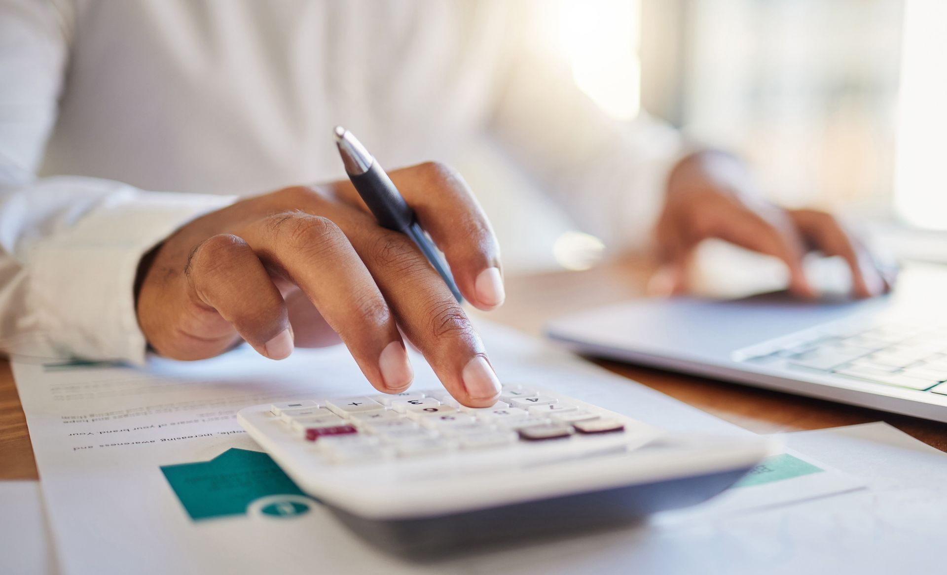 A person is using a calculator and a pen at the same time.