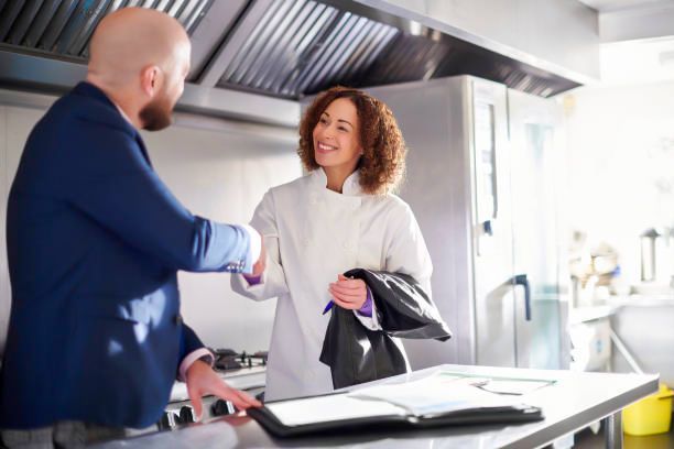 A man and a woman are shaking hands in a kitchen.