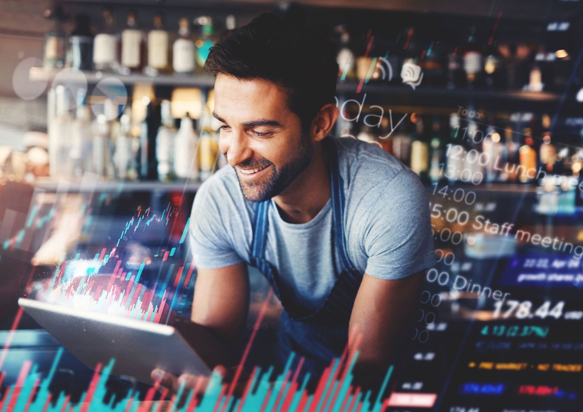 A man is smiling while looking at a tablet computer.