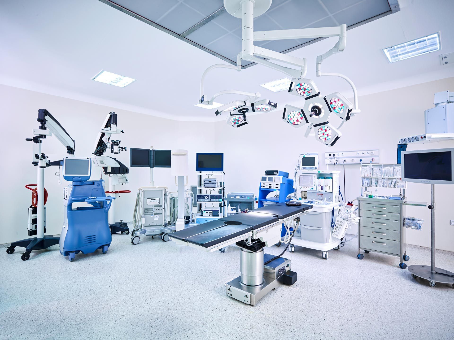 An empty operating room with a surgical table and lots of medical equipment.