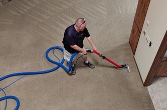 a man is cleaning a carpet with a vacuum cleaner .