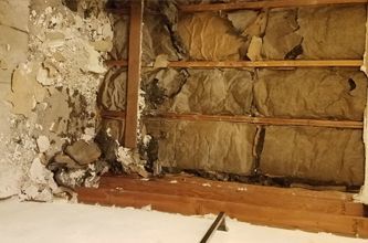 a room with a broken wall and a lot of insulation .