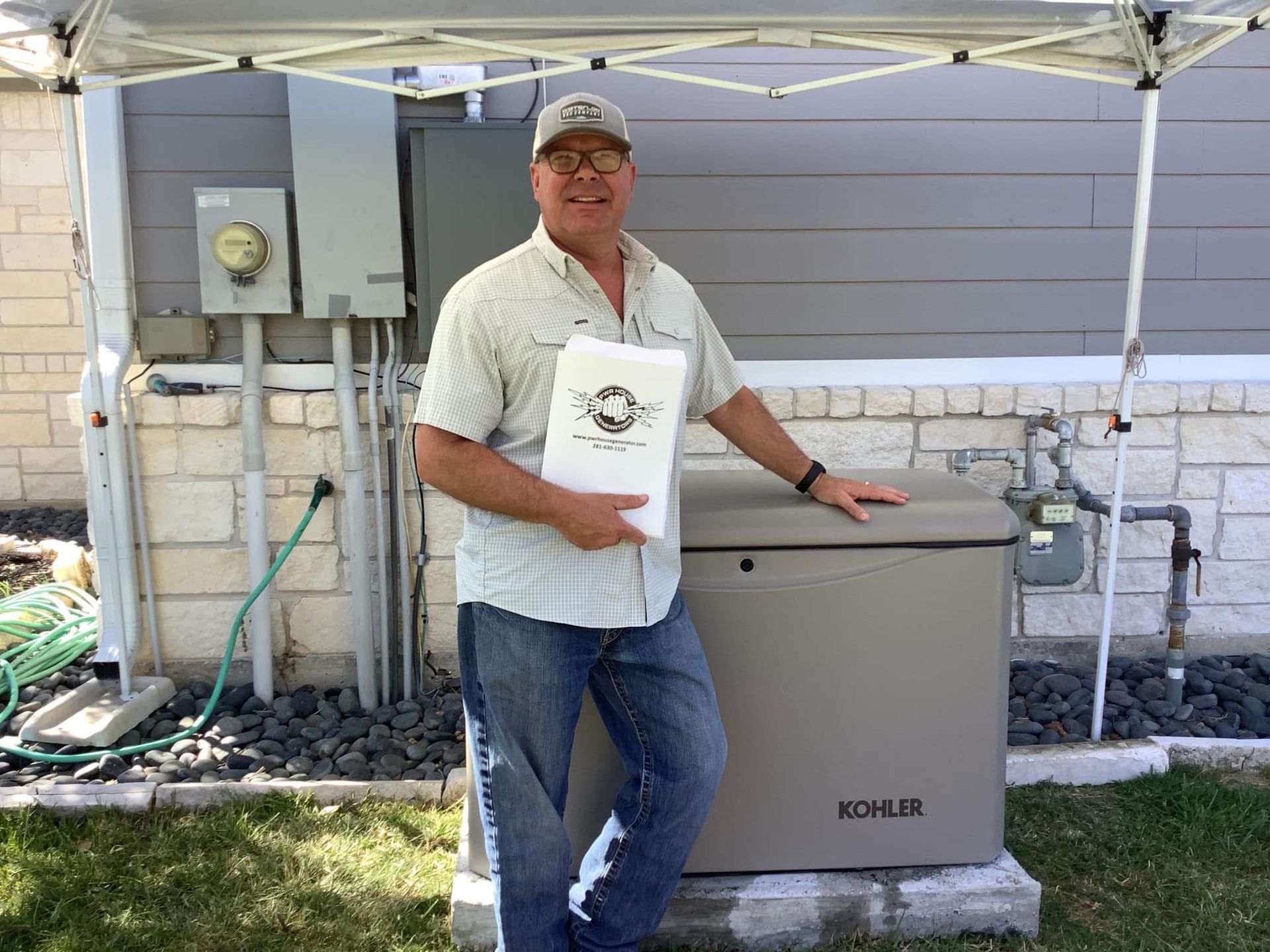 Man stands beside a Kohler generator outside a house, holding a bag.