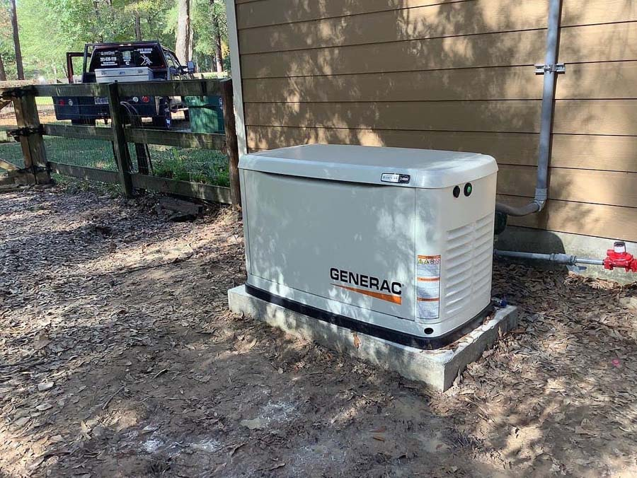 Generac generator on a concrete pad beside a beige building.