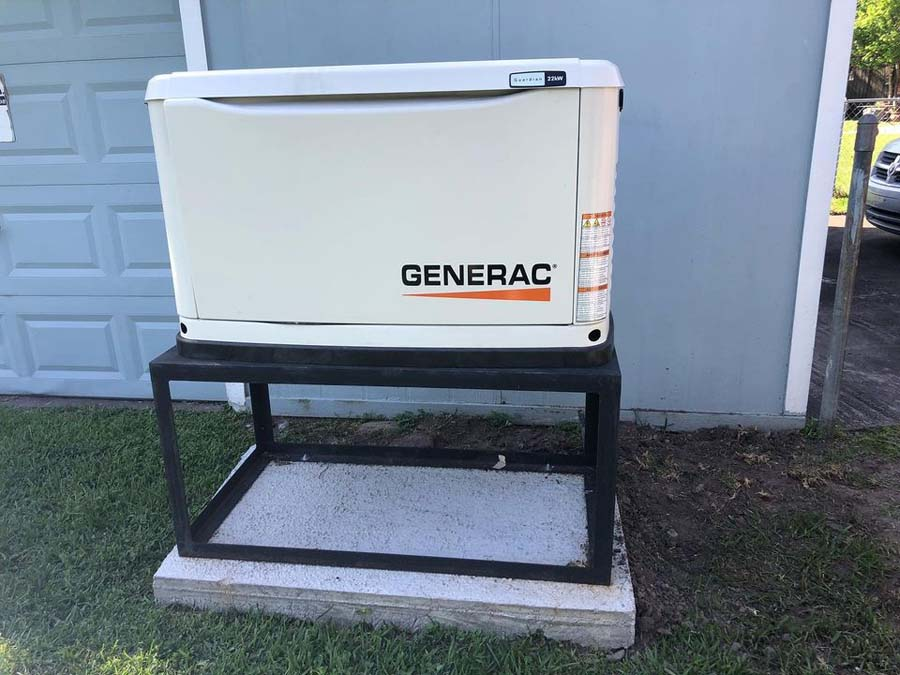 A Generac generator on a black metal frame outside a building with a garage door.