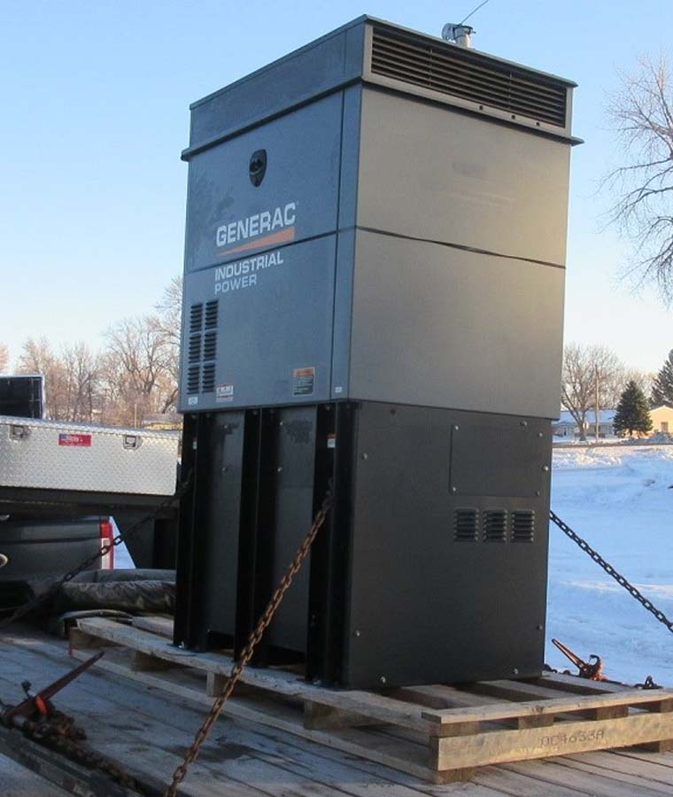 Large gray Generac industrial generator on a flatbed trailer in a snowy outdoor setting.