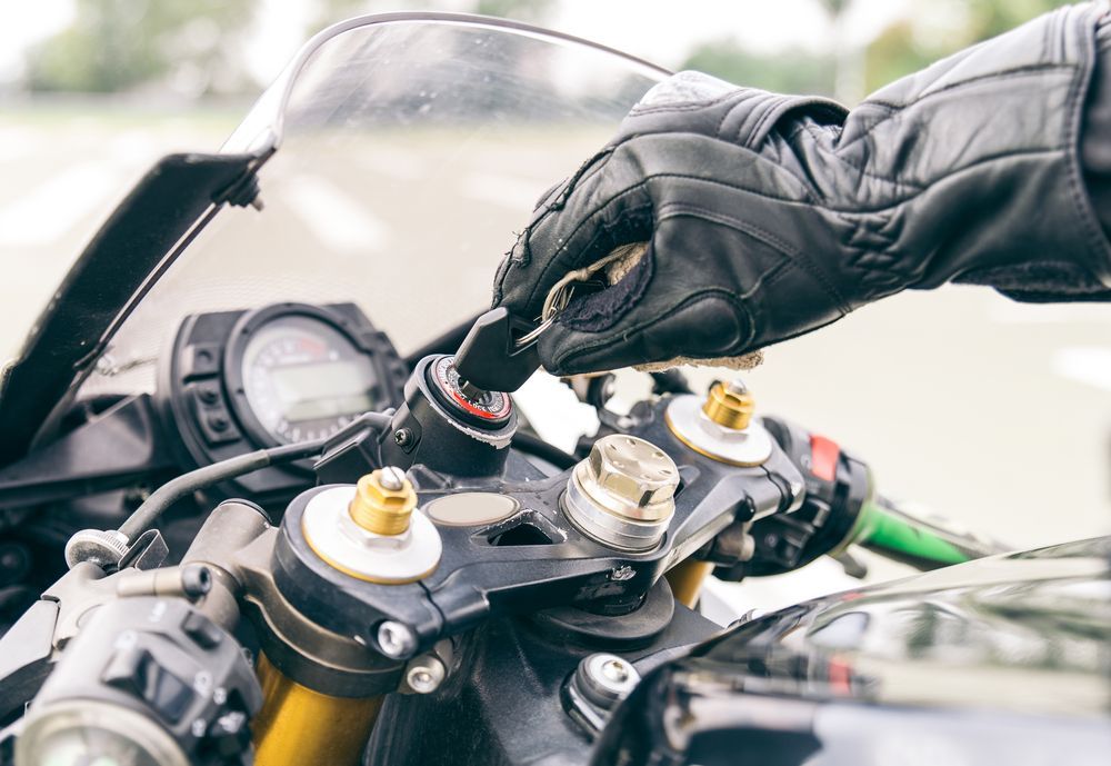 Gloved Hand Inserting Key Into Motorcycle Ignition — All Pro Locksmiths In Port Macquarie, NSW