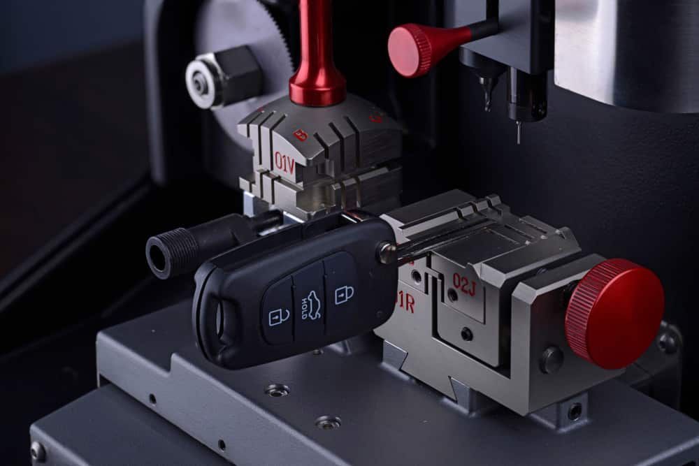 Key Cutting Machine Holding a Car Key, Red and Silver Metal — All Pro Locksmiths In Port Macquarie, NSW
