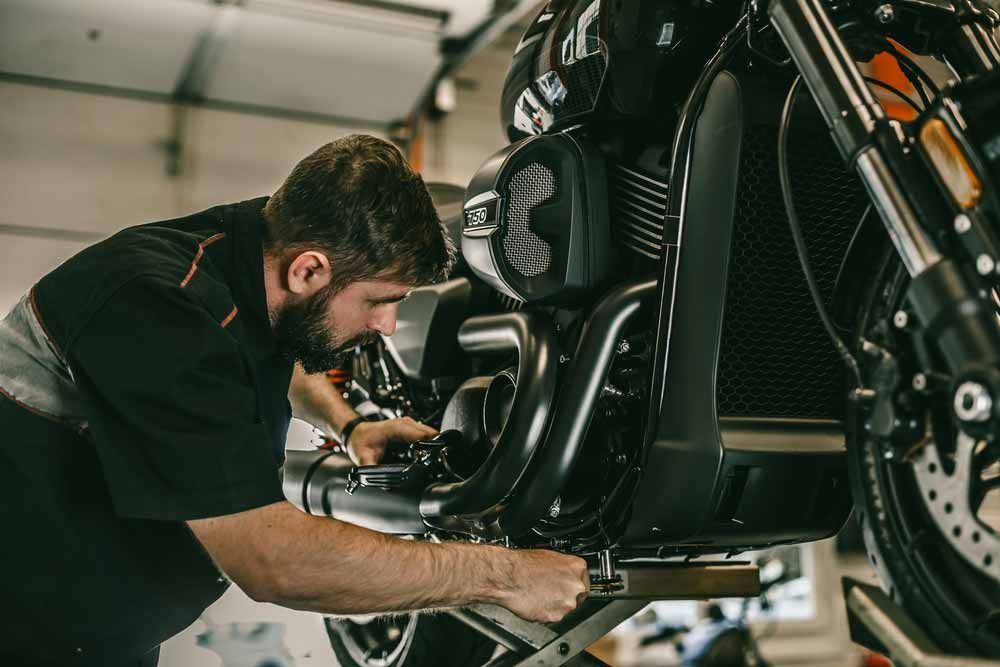 Mechanic Working on a Black Motorcycle in a Garage — All Pro Locksmiths In Port Macquarie, NSW