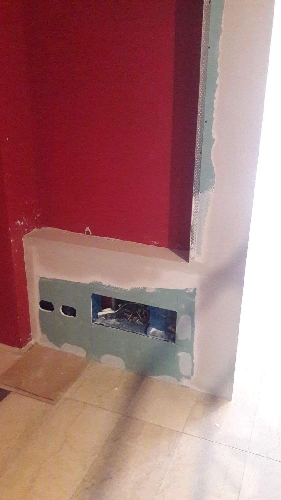 Una stanza con un muro rosso e un buco nel muro.