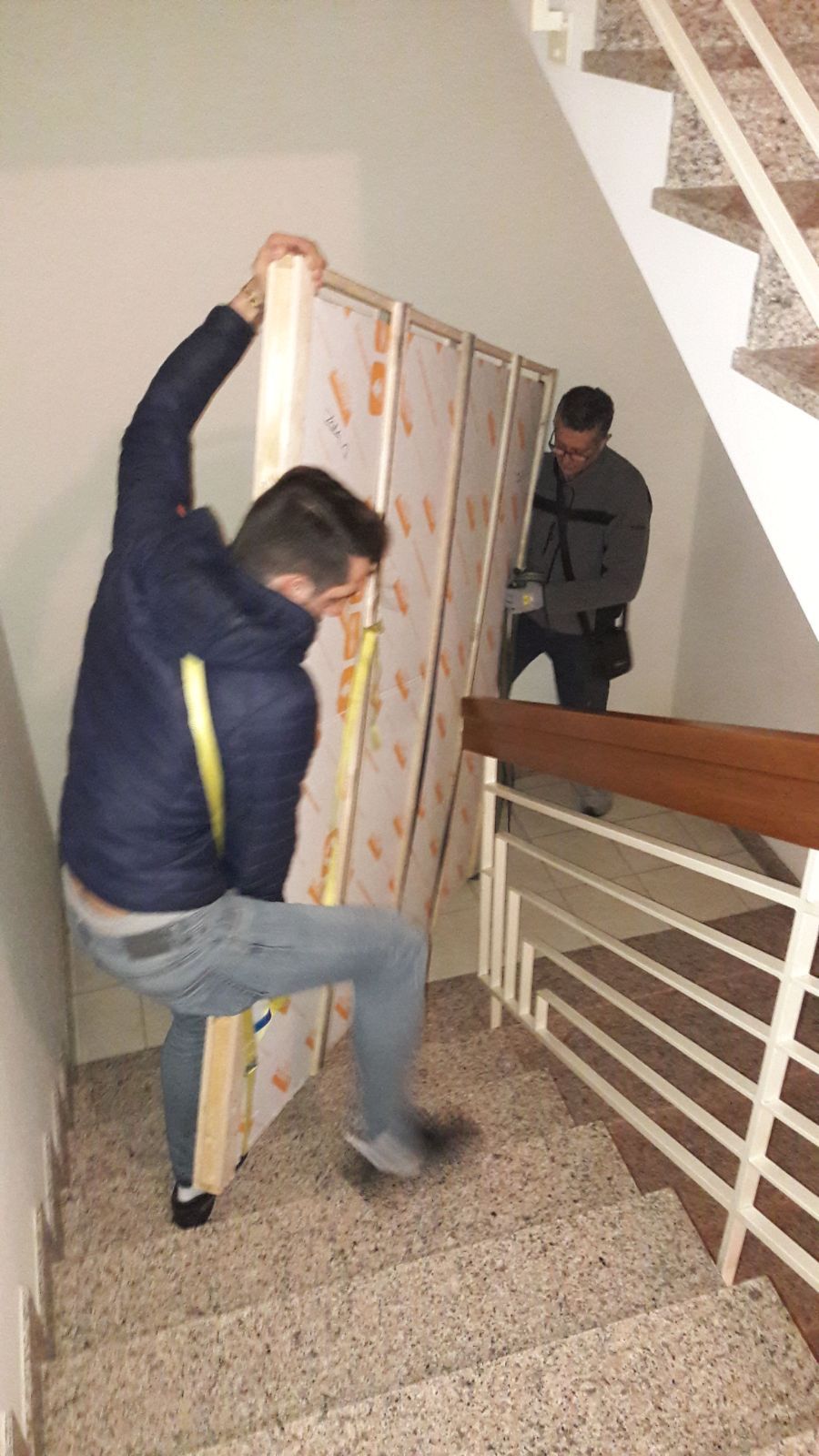 Un uomo sta trasportando un grosso pezzo di legno su per una rampa di scale.