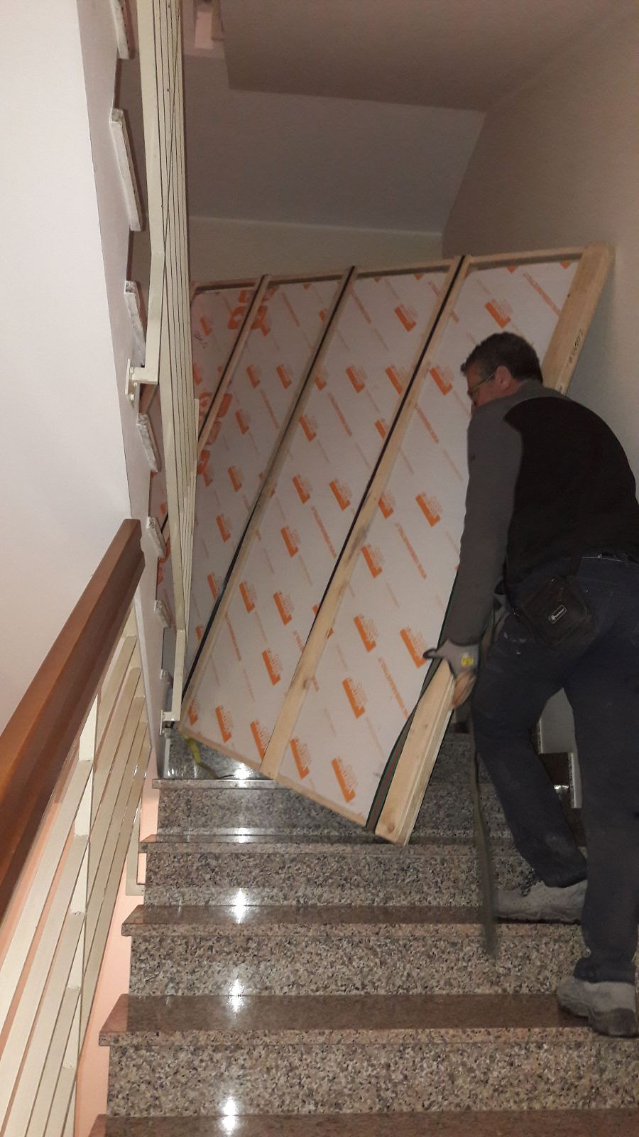 Un uomo sta trasportando un grosso pezzo di legno su per una rampa di scale.