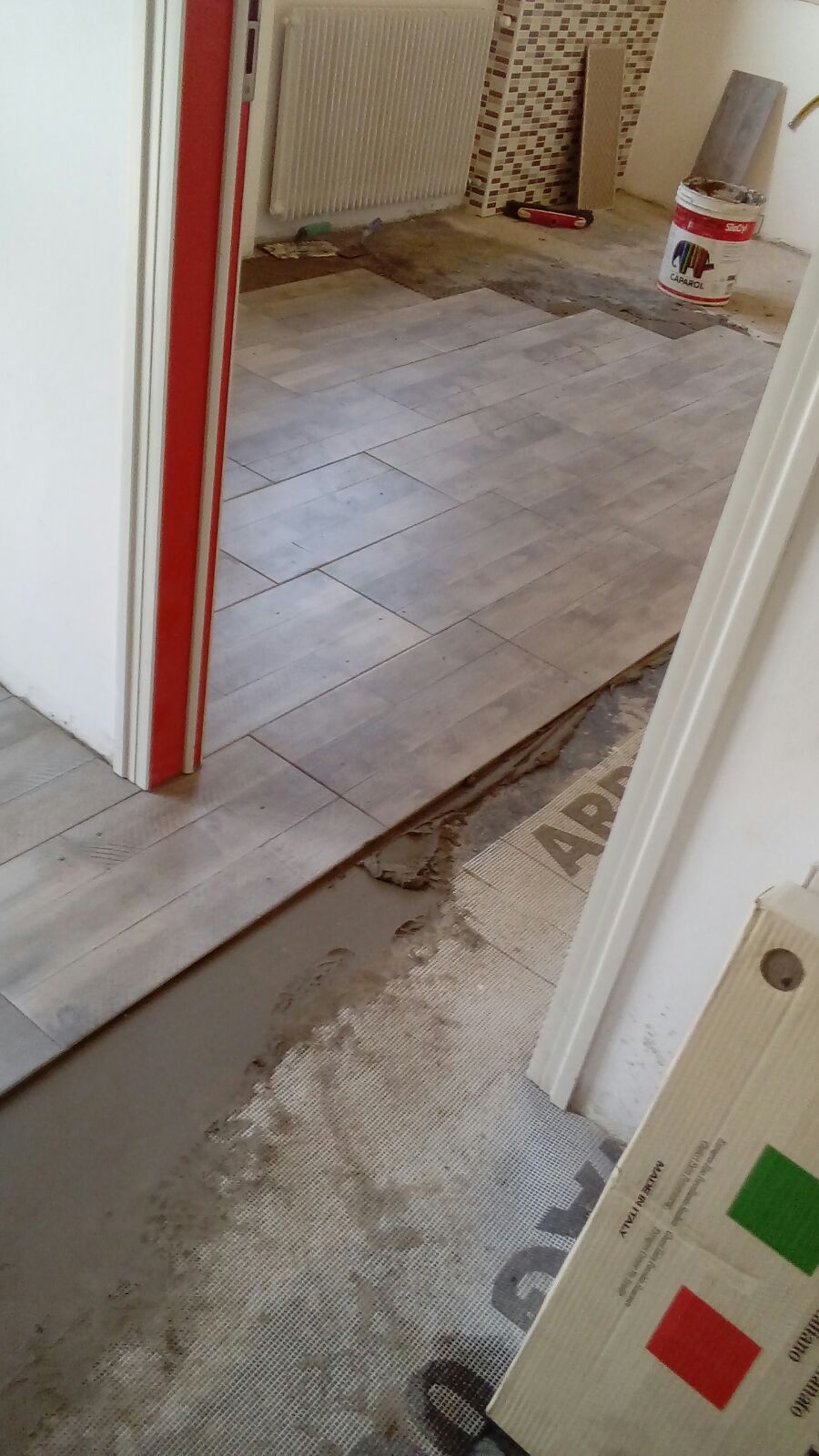 In una stanza accanto a una porta viene installato un pavimento piastrellato.