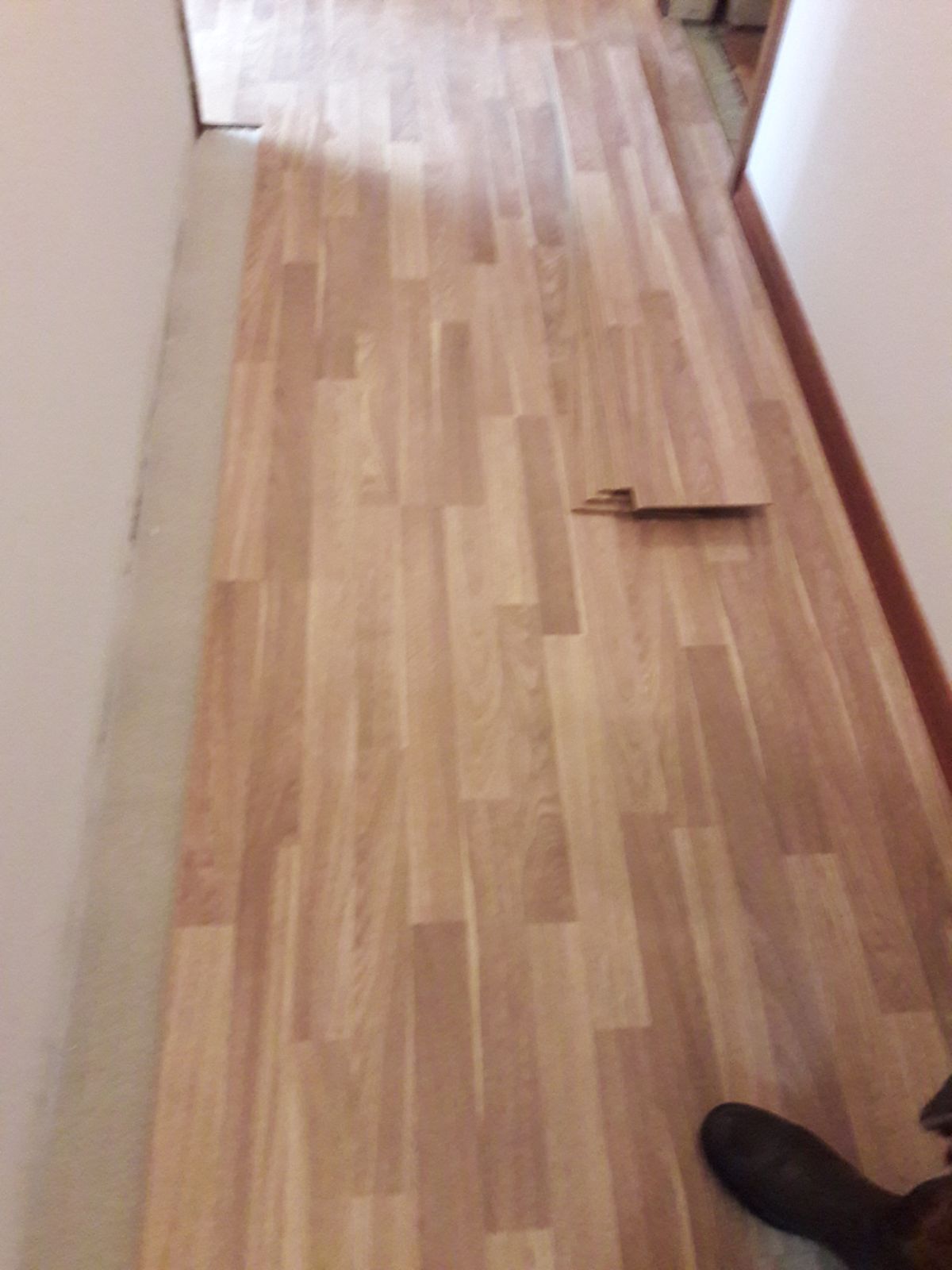 Una persona è in piedi su un pavimento di legno in un corridoio.